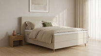 Bruno Boxspringbett mit Linea-Kopfteil, in Beige, Winkelansicht, im Wohnraum, mit Topper, mit Füßen aus nordischer Eiche