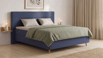 Bruno Boxspringbett mit Linea-Kopfteil, in Blau, Winkelansicht, im Wohnraum, mit Topper, mit Füßen aus nordischer Eiche